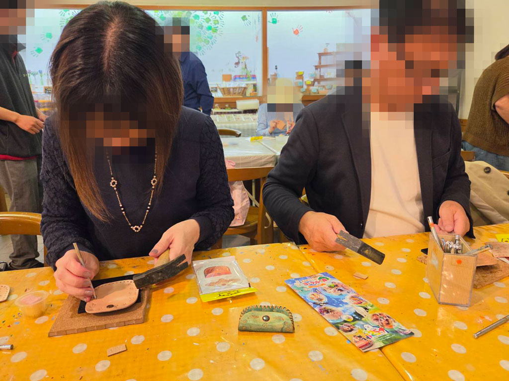 革の小銭入れづくりを楽しむ恋バスツアー参加者